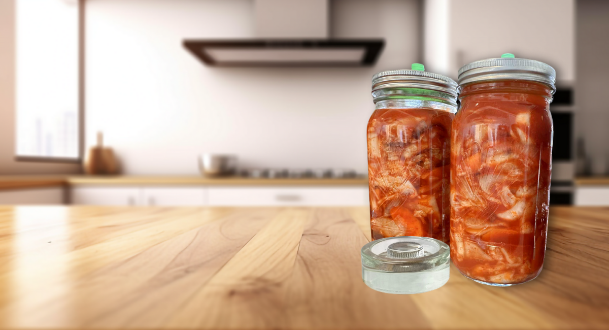 Two jars of kimchi on a kitchen counter with a blurred kitchen background